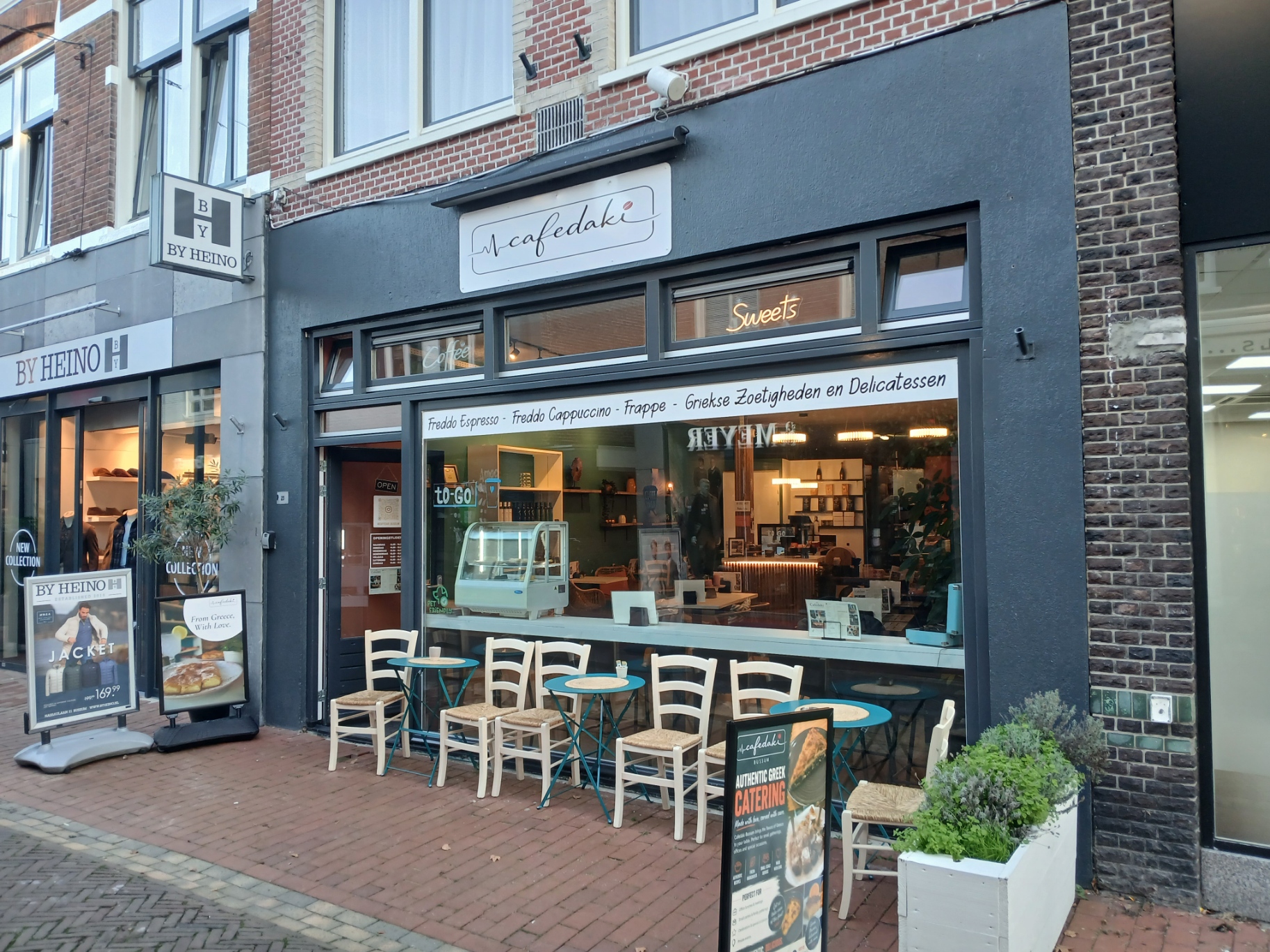 De blauwe gevel van Cafedaki Bussum aan de Nassaulaan met het Cafedaki-woordmerk en terras