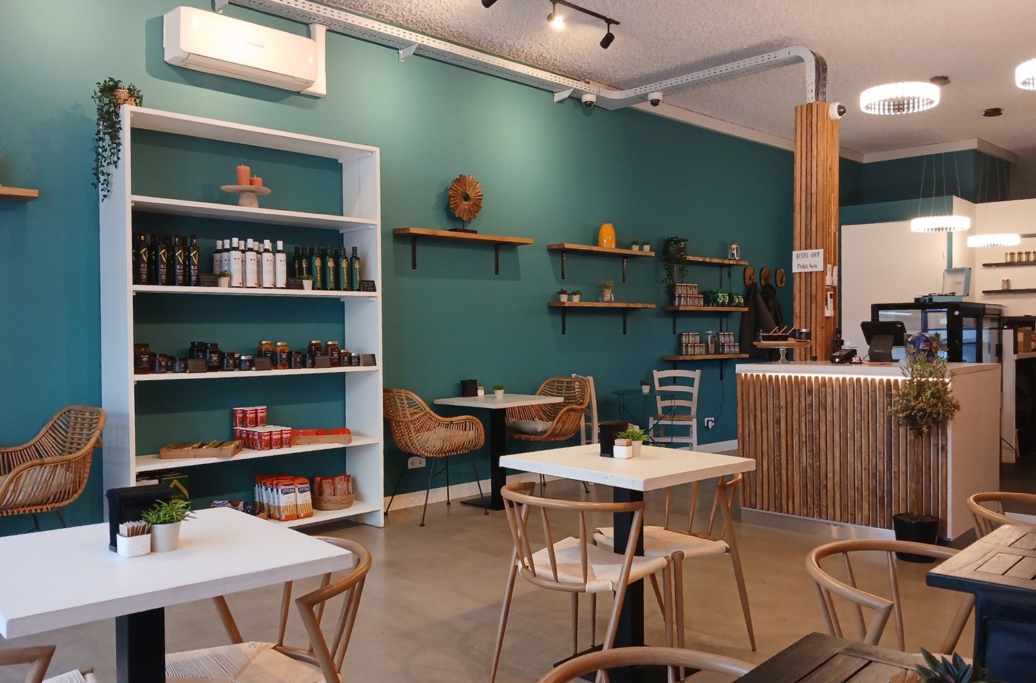 Zitplaatsen en bar in het interieur van Cafedaki met blauwgroene wanden en houten meubels