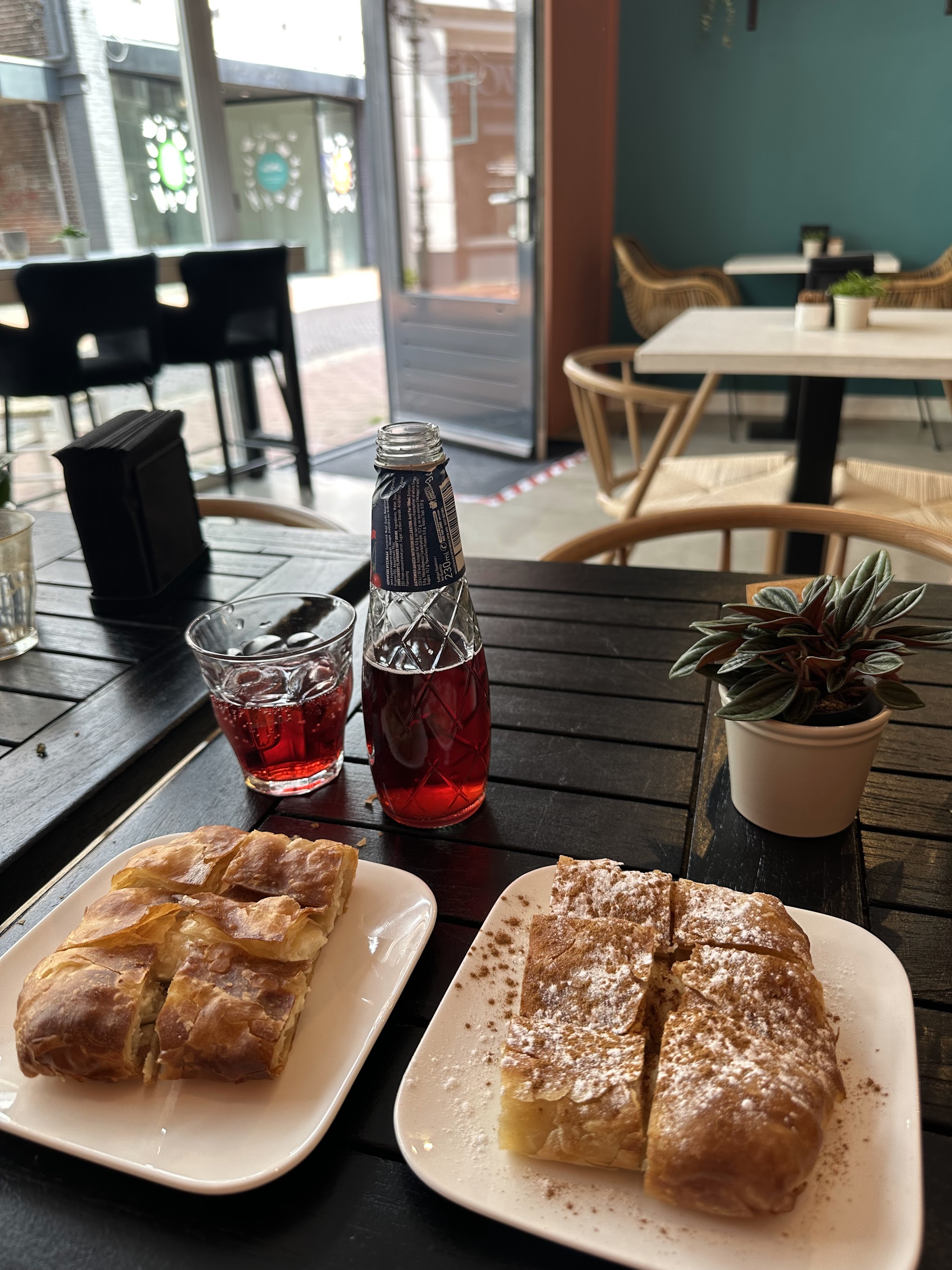 Twee borden met Grieks gebak en een rood drankje op het terras